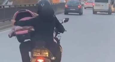 Motosiklet üzerinde bebeği pusetiyle taşıdı