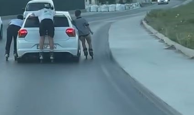Otomobile tutunarak ilerleyen patenli çocuklar kamerada