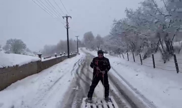 Yağışı eğlenceye dönüştürdü: Karla kaplı yolda ahşap paletle kayak yaptı